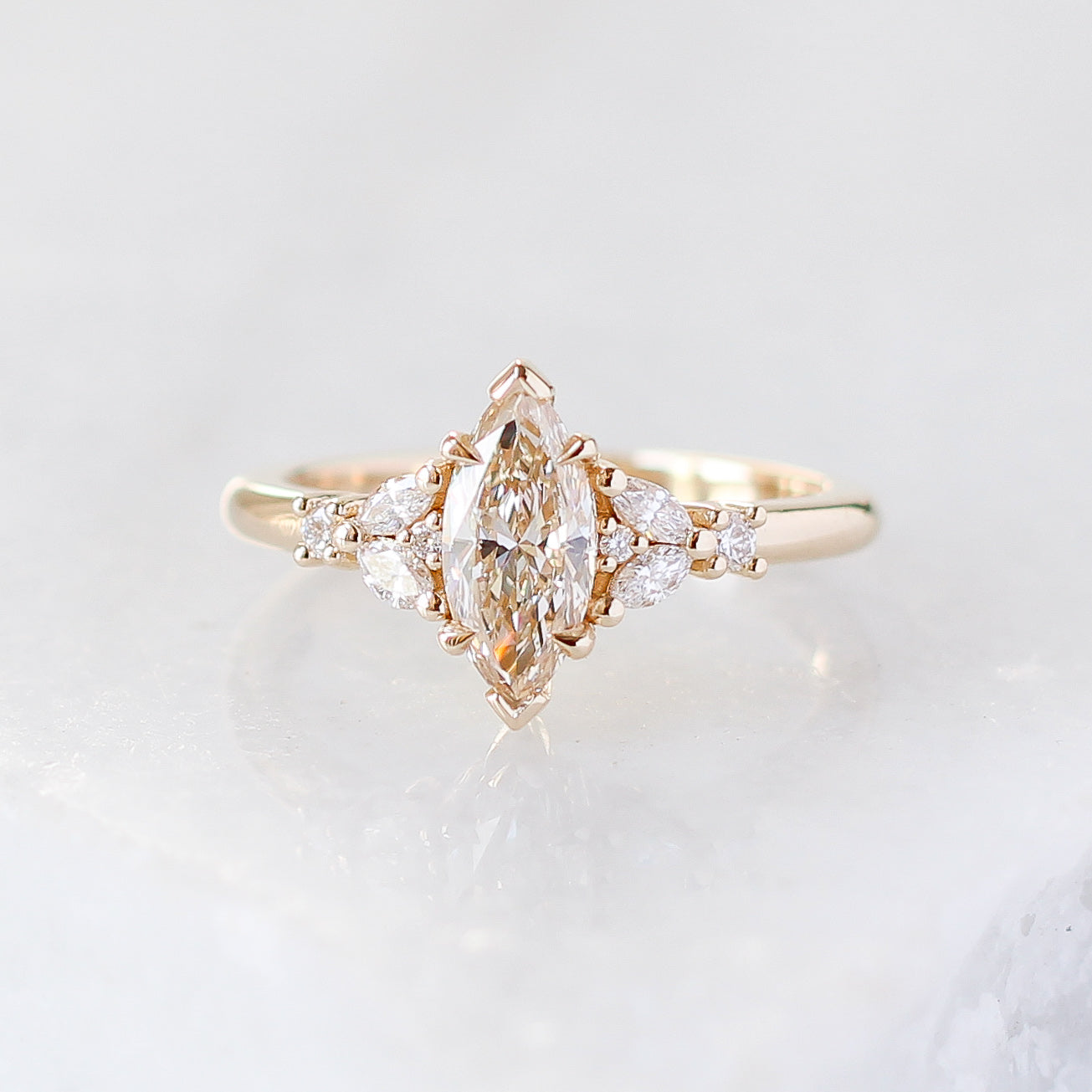 Yellow gold ring with a champagne marquise cut diamond and white diamond clusters, front view