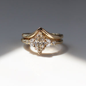 Yellow gold ring with a champagne marquise cut diamond and white diamond clusters stacked with pointed wedding band, front view