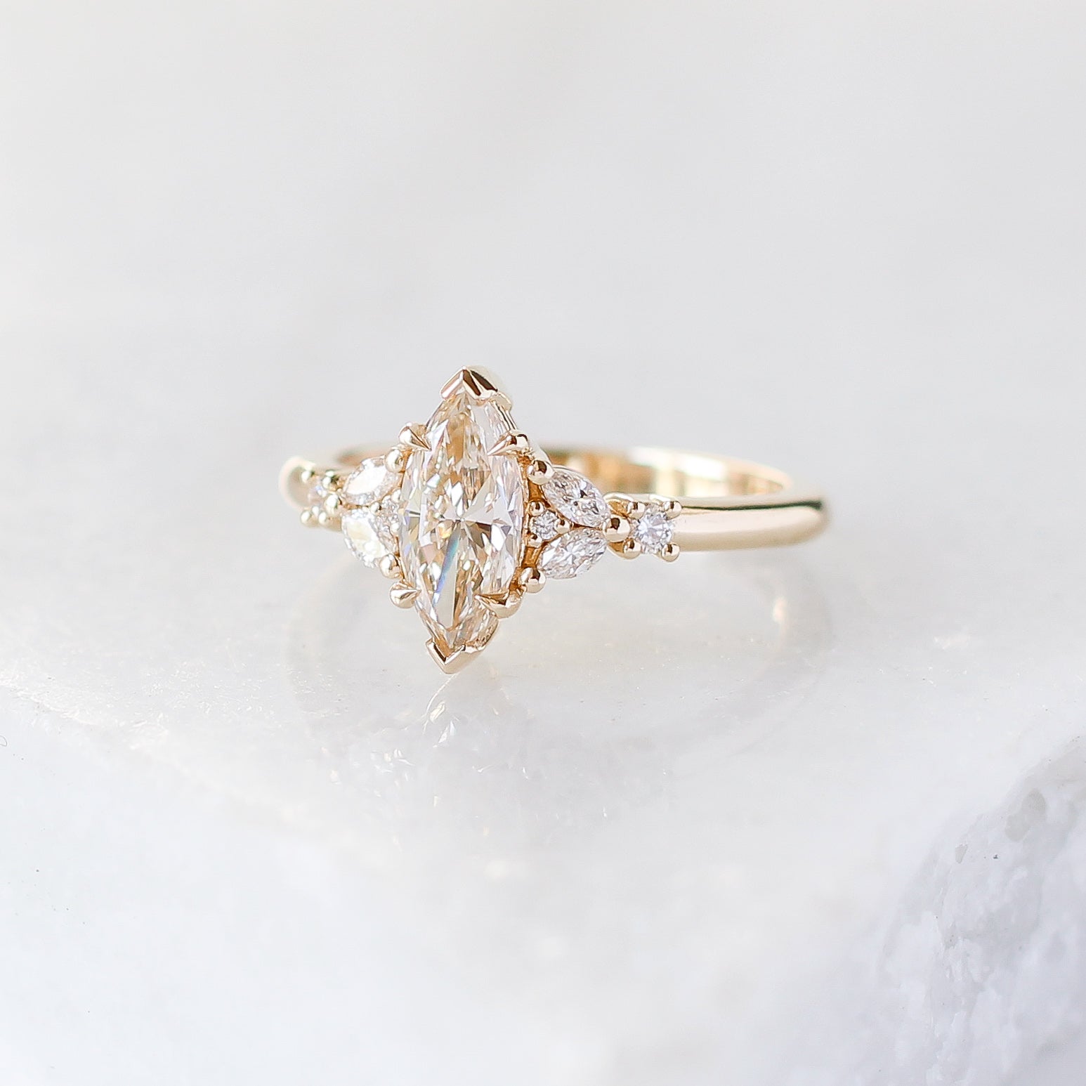 Yellow gold ring with a champagne marquise cut diamond and white diamond clusters, quarter view