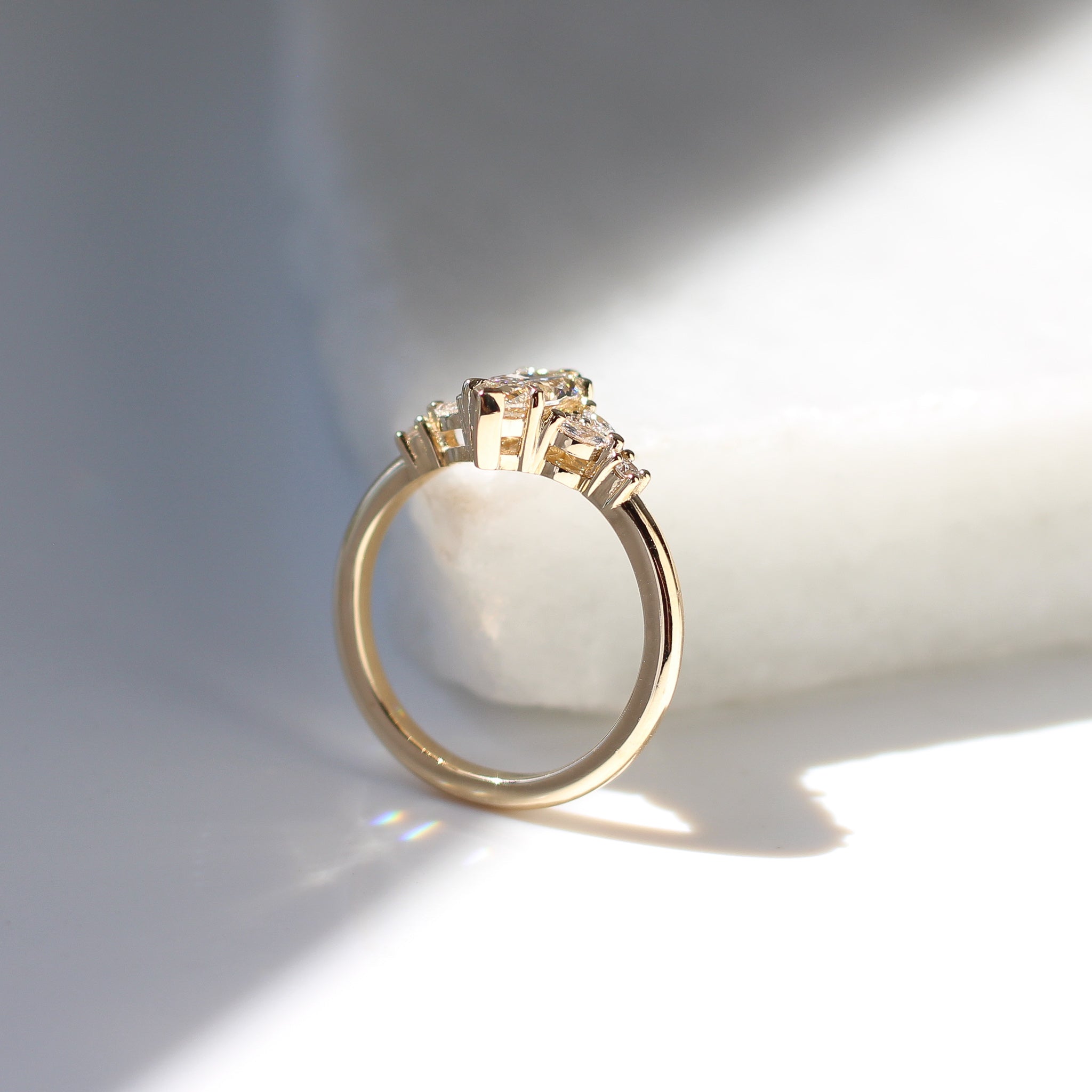 Yellow gold ring with a champagne marquise cut diamond and white diamond clusters, side view