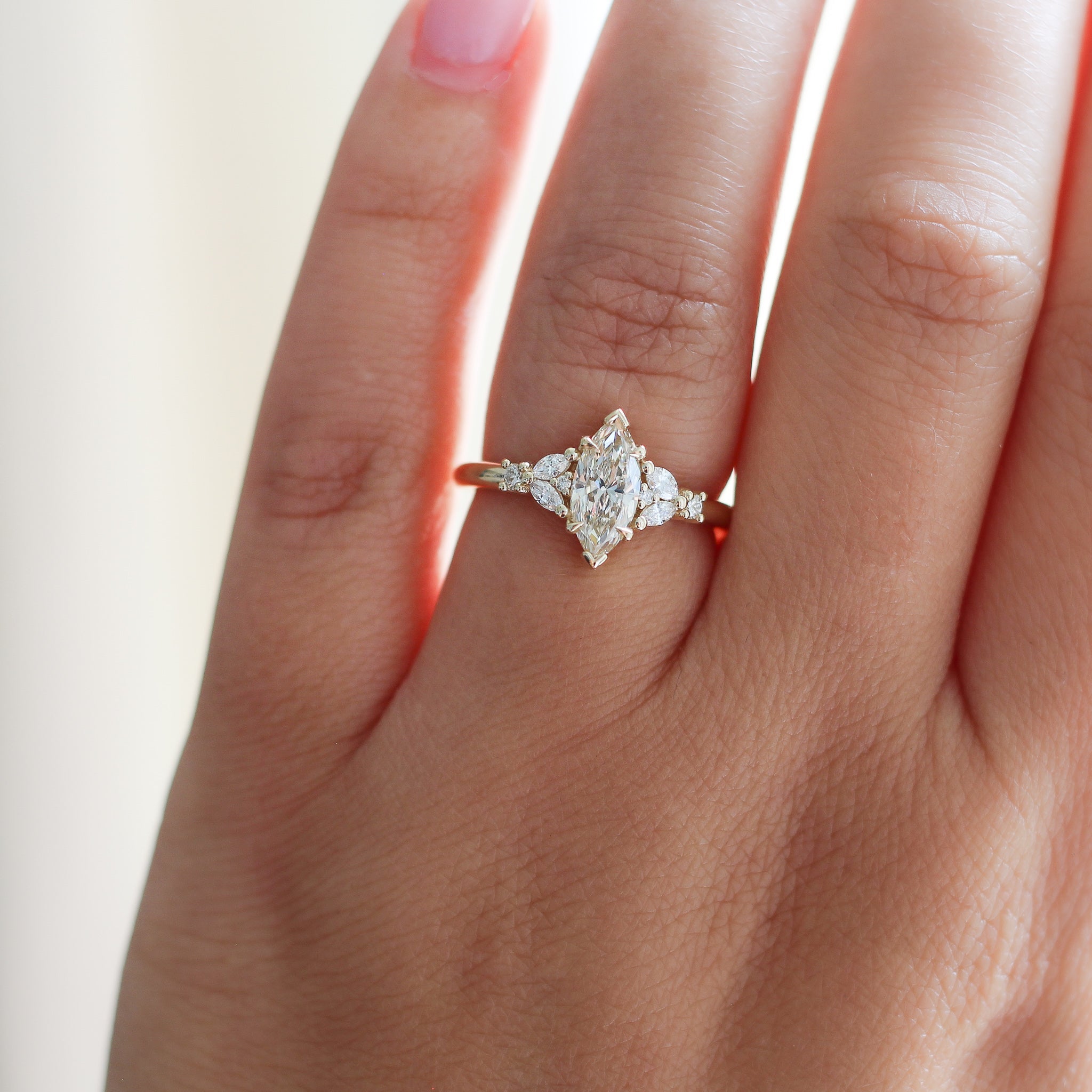Yellow gold ring with a champagne marquise cut diamond and white diamond clusters, on hand