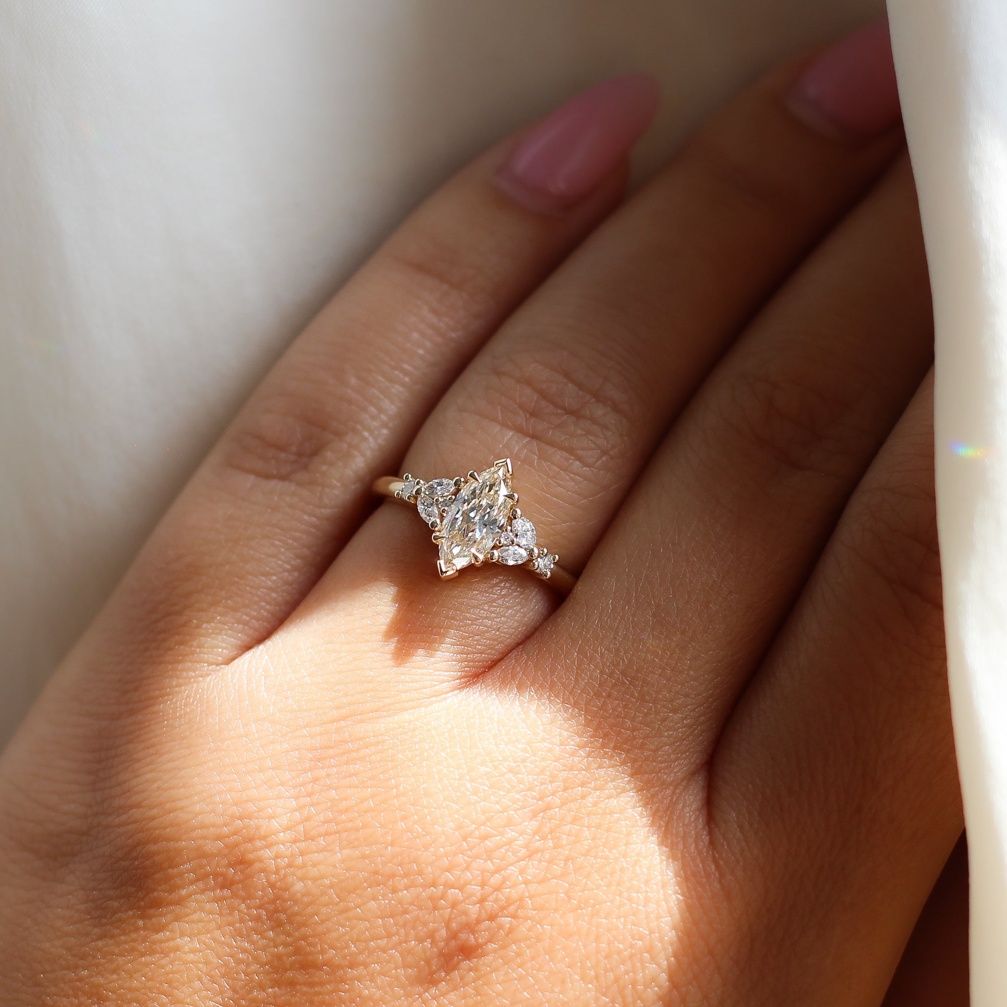 Yellow gold ring with a champagne marquise cut diamond and white diamond clusters, on hand
