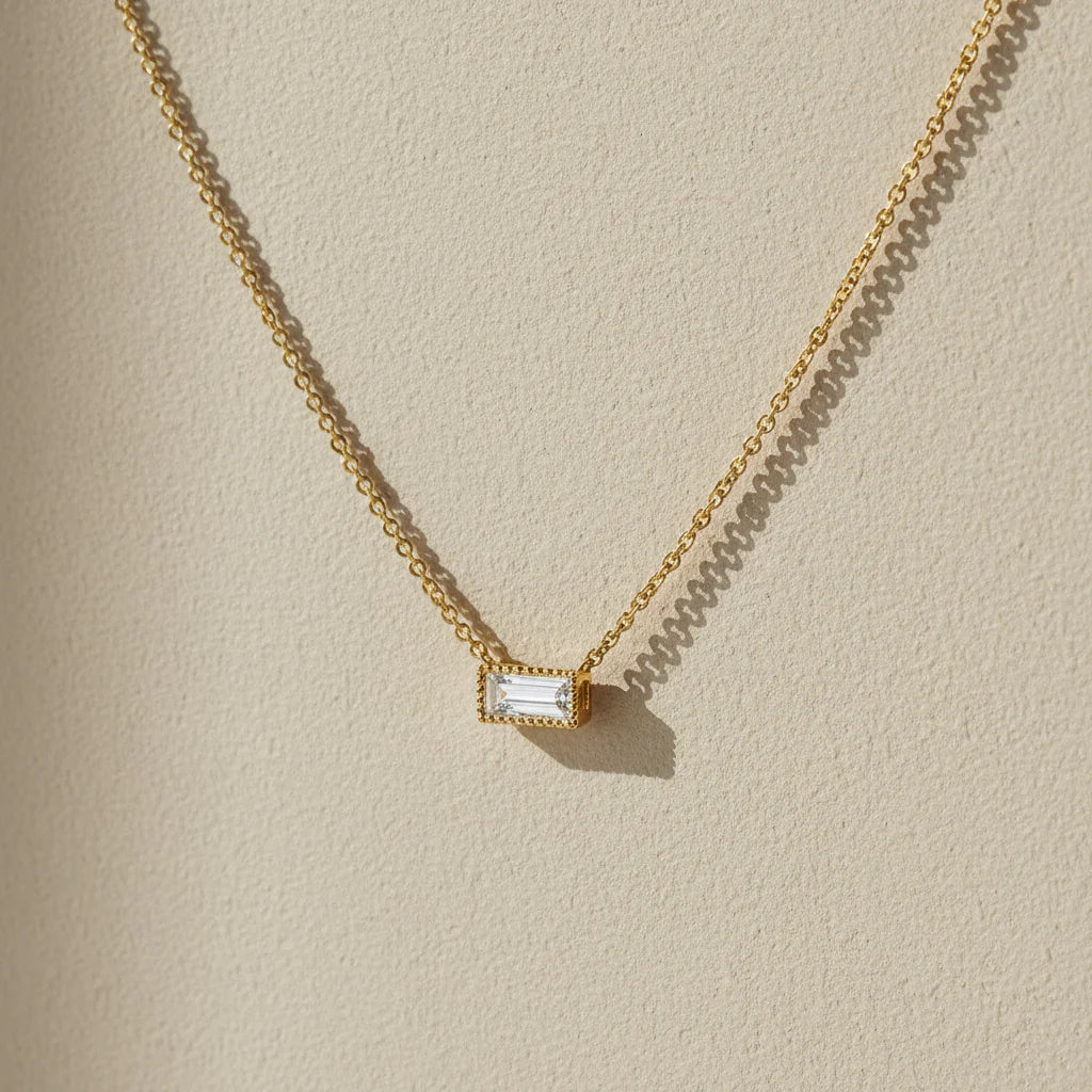 Gold necklace with a rectangular diamond pendant on a white background