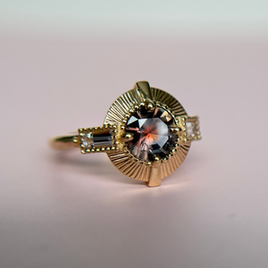 Yellow Gold ring with a round dusky pink sapphire and diamond accent stones on a gradient background