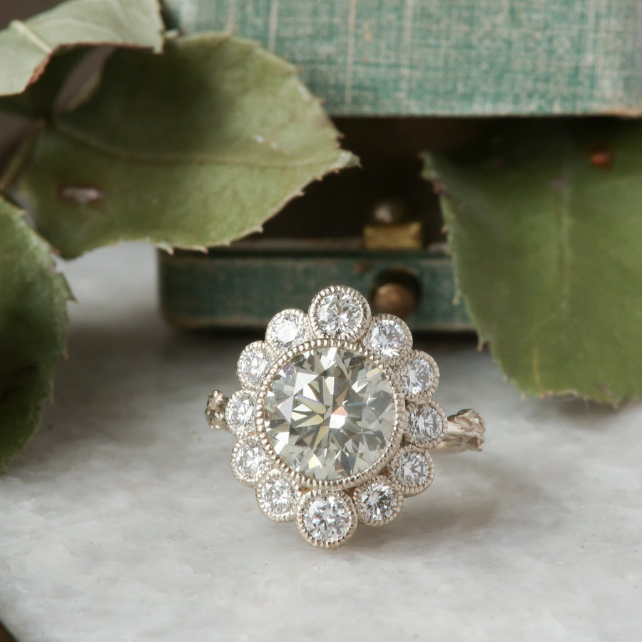 An antique inspired flower diamond halo engagement ring with natural light gray diamond center in white gold.